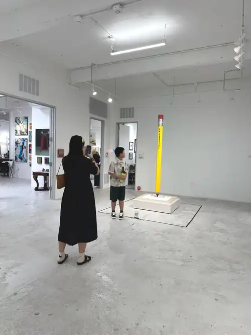 High school students and teacher observing a height measuring device in an art gallery setting.